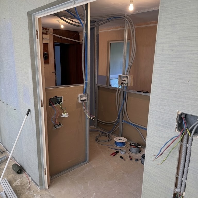 Chantier de rénovation réseau Lyon : passage des gaines électriques et câbles Ethernet Cat 7 entre les montants d'un futur bureau en télétravail à Lyon 5.