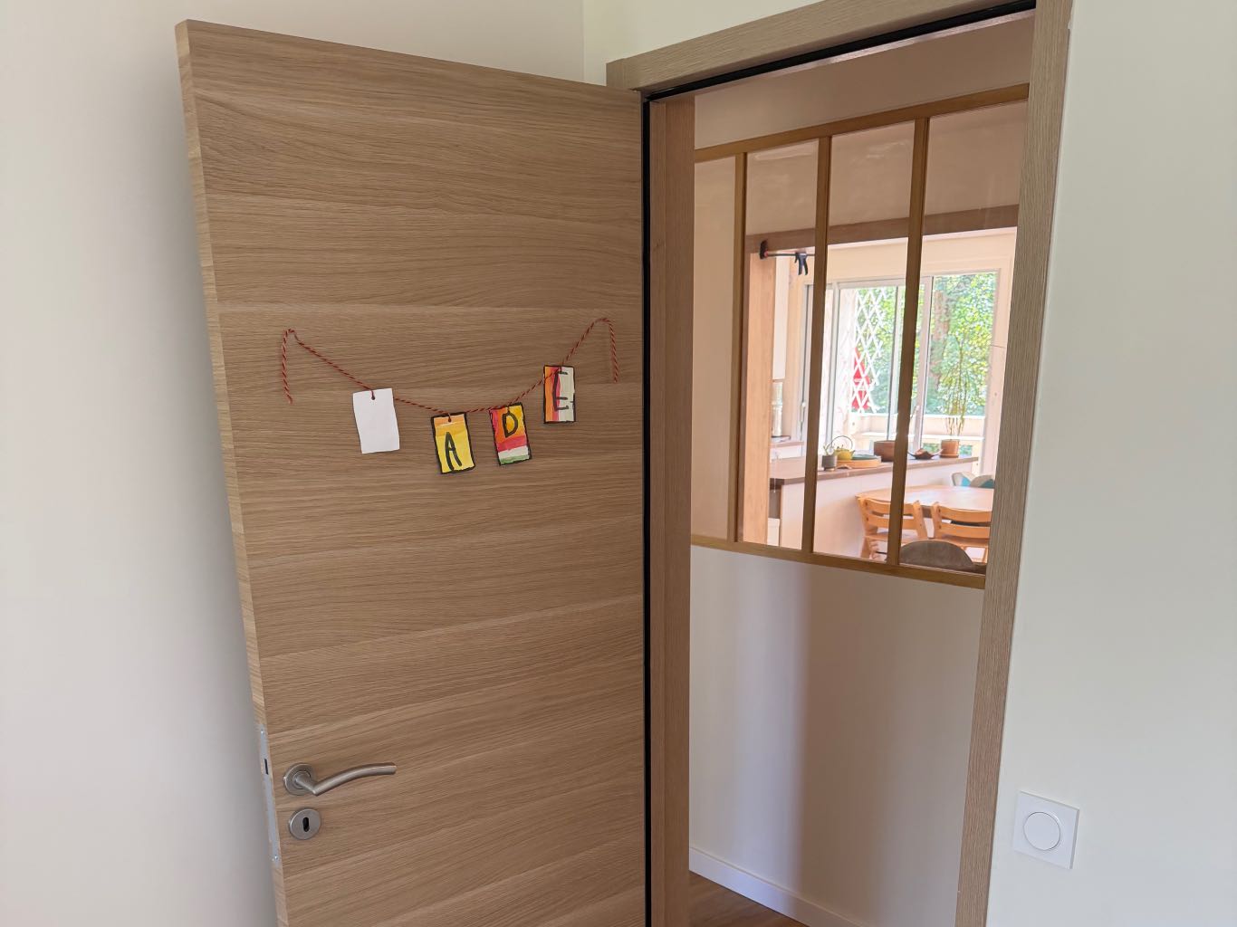 Porte de chambre acoustique avec joint guillotine automatique, plancher bois et couloir lumineux, confort isophonique rénovation appartement années 60 Lyon.