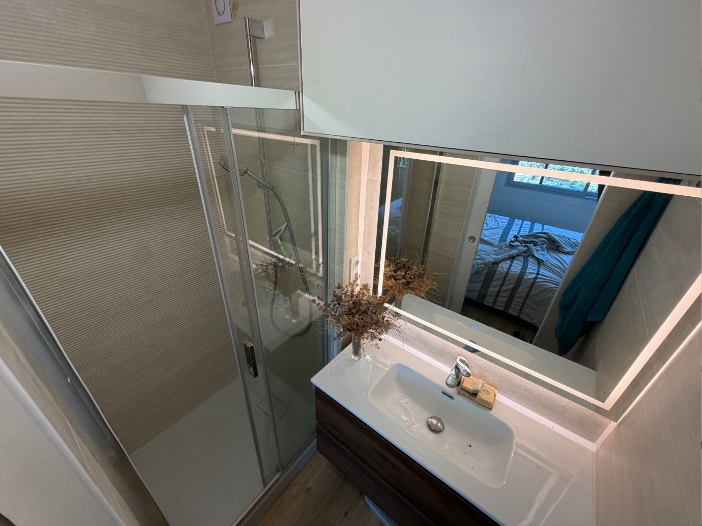 Petite salle d'eau optimisée avec douche et miroir rétroéclairé, créée sur-mesure pour la nouvelle suite parentale d'un appartement à Lyon 5.