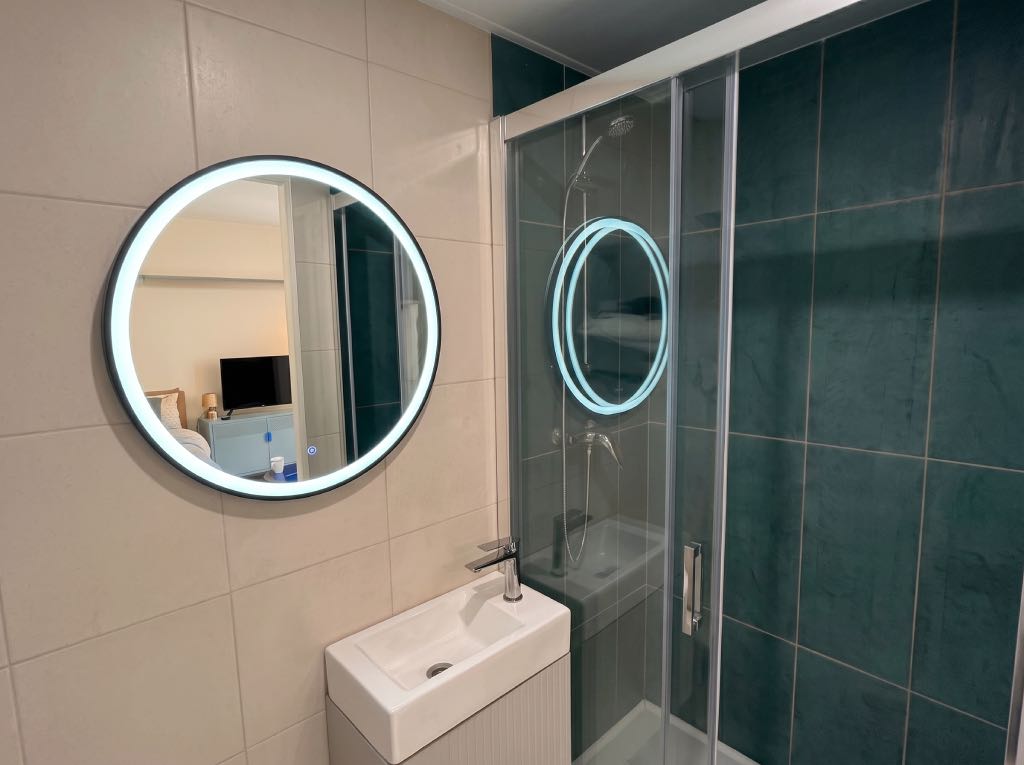 Aménagement d'une petite salle de bain de 2m² avec douche sur-mesure et miroir LED dans une maison rénovée à Lyon.