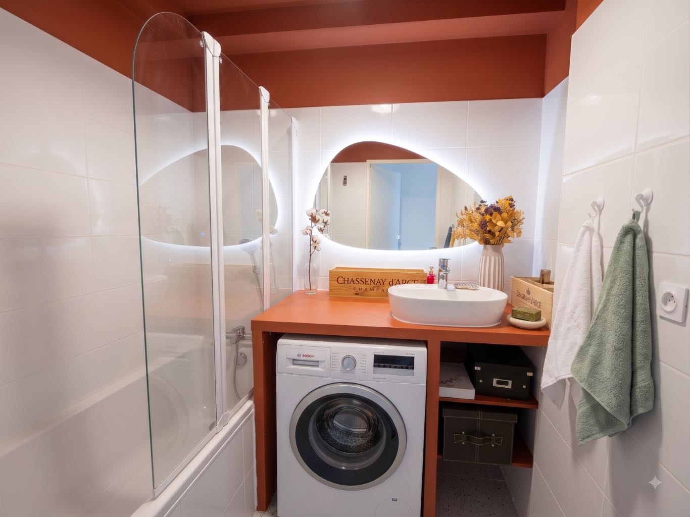 Petite salle de bain enfants colorée avec plan de travail sur-mesure terracotta, vasque bol, miroir organique rétroéclairé, baignoire et lave-linge intégré, rénovée à Lyon 5.