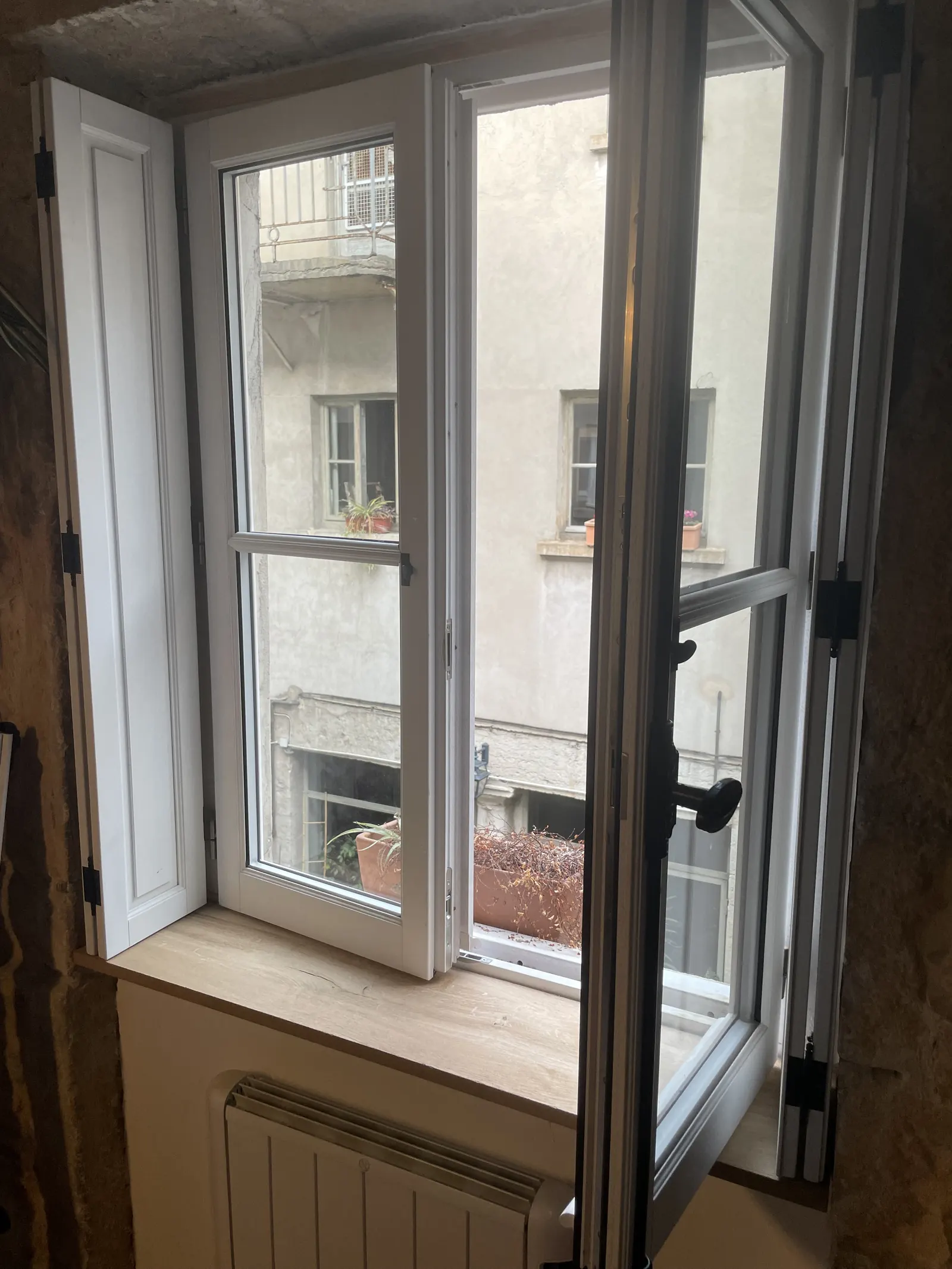 Rénovation d'appartement à Lyon : quand faut-il l'accord de l'ABF ? 3 Fenêtre en bois blanc ouverte avec petits bois et poignée à espagnolette, rue Royale à Lyon